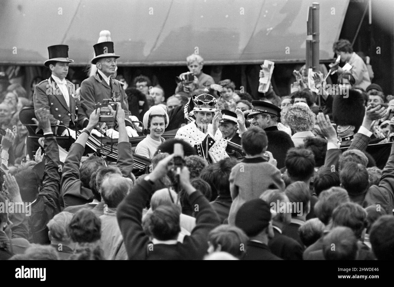 Die Investitur von Prinz Charles auf Caernarfon Castle. Caernarfon, Wales. Auf dem Bild ist Prinz Charles, der neu investierte Prinz von Wales, mit seiner Krone und seinen Roben, nach der Zeremonie von der Burg weggefahren. Im Wagen sind auch Königin Elizabeth II. Und Prinz Philip abgebildet. 1.. Juli 1969. Stockfoto