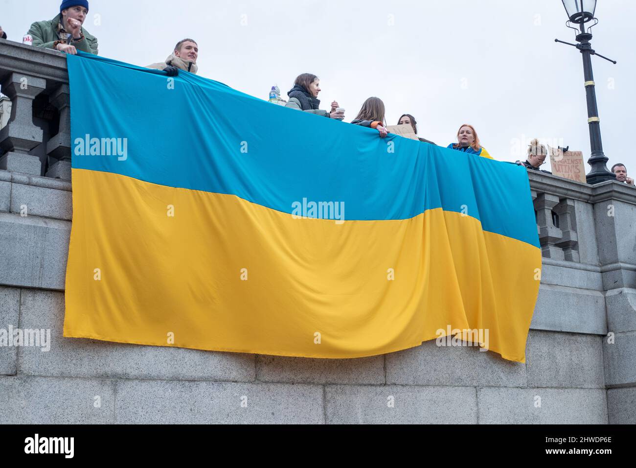 LONDON, 05 2022. MÄRZ, während eines Protestes gegen die russische Invasion in der Ukraine auf dem Trafalgar Square hängen Demonstranten die ukrainische Flagge über eine Mauer.Quelle: Lucy North/Alamy Live News Stockfoto