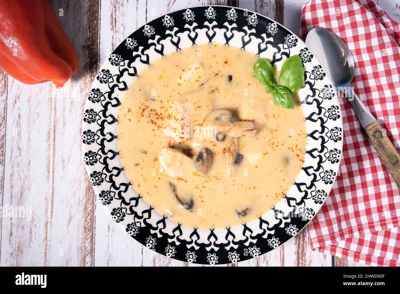 Eine hausgemachte Creme aus Hühnchen- und Pilzsuppe oder Hühnerfrikassee nach französischem Stil in einer Suppenschüssel auf einem Holztisch. Luftaufnahme Stockfoto