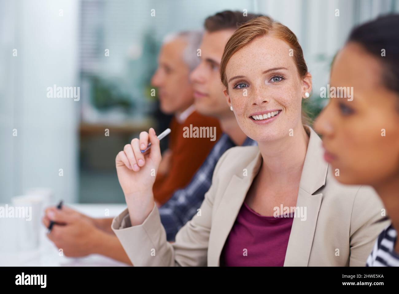 Mit diesem Team an die Spitze. Aufnahme einer Geschäftsfrau, die während eines Treffens mit ihren Kollegen lächelt. Stockfoto
