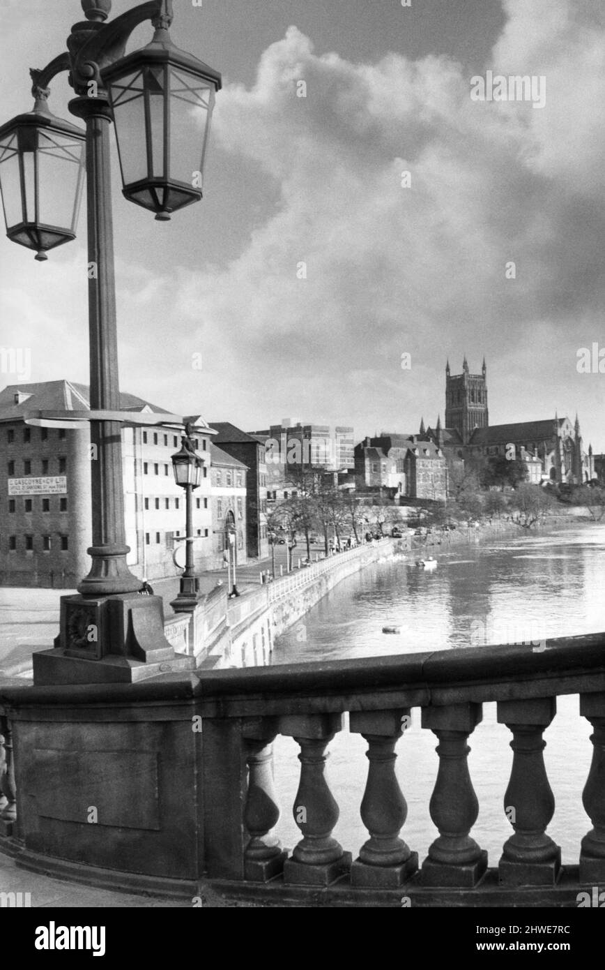 Malerisches Worcester, das an einem der hübschen Lampenstandards auf der New Road-Brücke vorbei blickt, zum baumgesäumten South Quay und zur Kathedrale, die sich im winterhohen Wasser des Flusses Severn widerspiegelt. 1970. Stockfoto