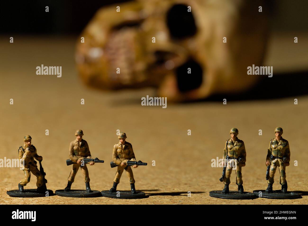 Spielzeug Soldaten mit einem menschlichen Schädel auf dem Hintergrund. Kriegskonzeption Fotografie Stockfoto
