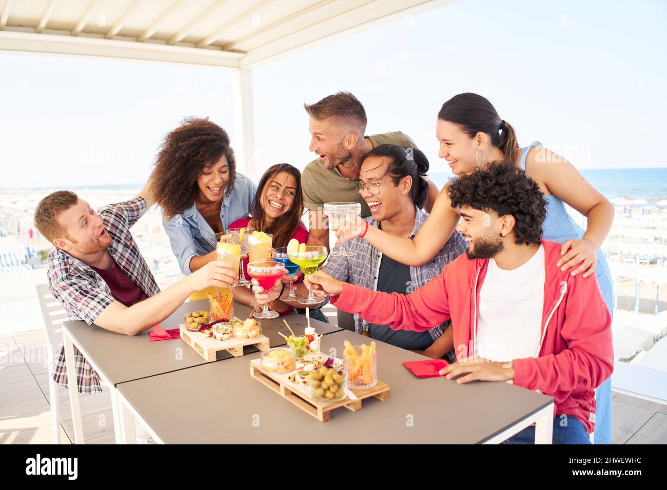 Multirassische Freunde junger Menschen, die gemeinsam auf dem Dach Cocktails toasten. Konzept des Lebensstils der sozialen Gemeinschaft Stockfoto
