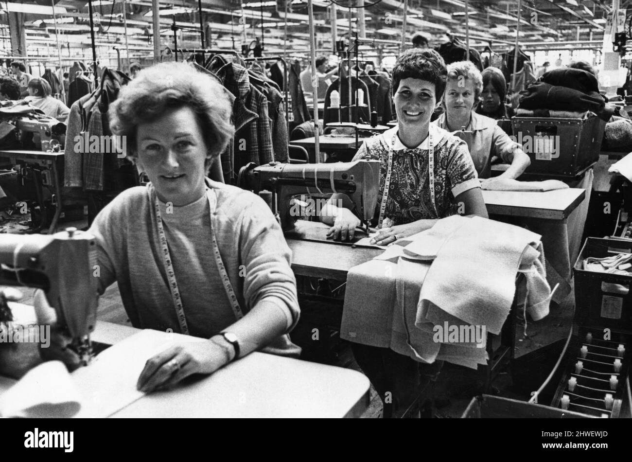 Maschinell arbeitende Mütter produzieren weiterhin in der Steingberg and Sons Kittel Factory in Hawthorn, Pontypridd, während ihre Kinder im nahe gelegenen Kindergarten in einem Klassenzimmer der Hawthorn County Secondary School versorgt werden. Die geschulten Vorgesetzten wurden von der Firma für die Betreuung der Schulferien-Klasse mit 25 Jungen und Mädchen im Alter zwischen fünf und zehn Jahren bezahlt. 20.. August 1969. Stockfoto