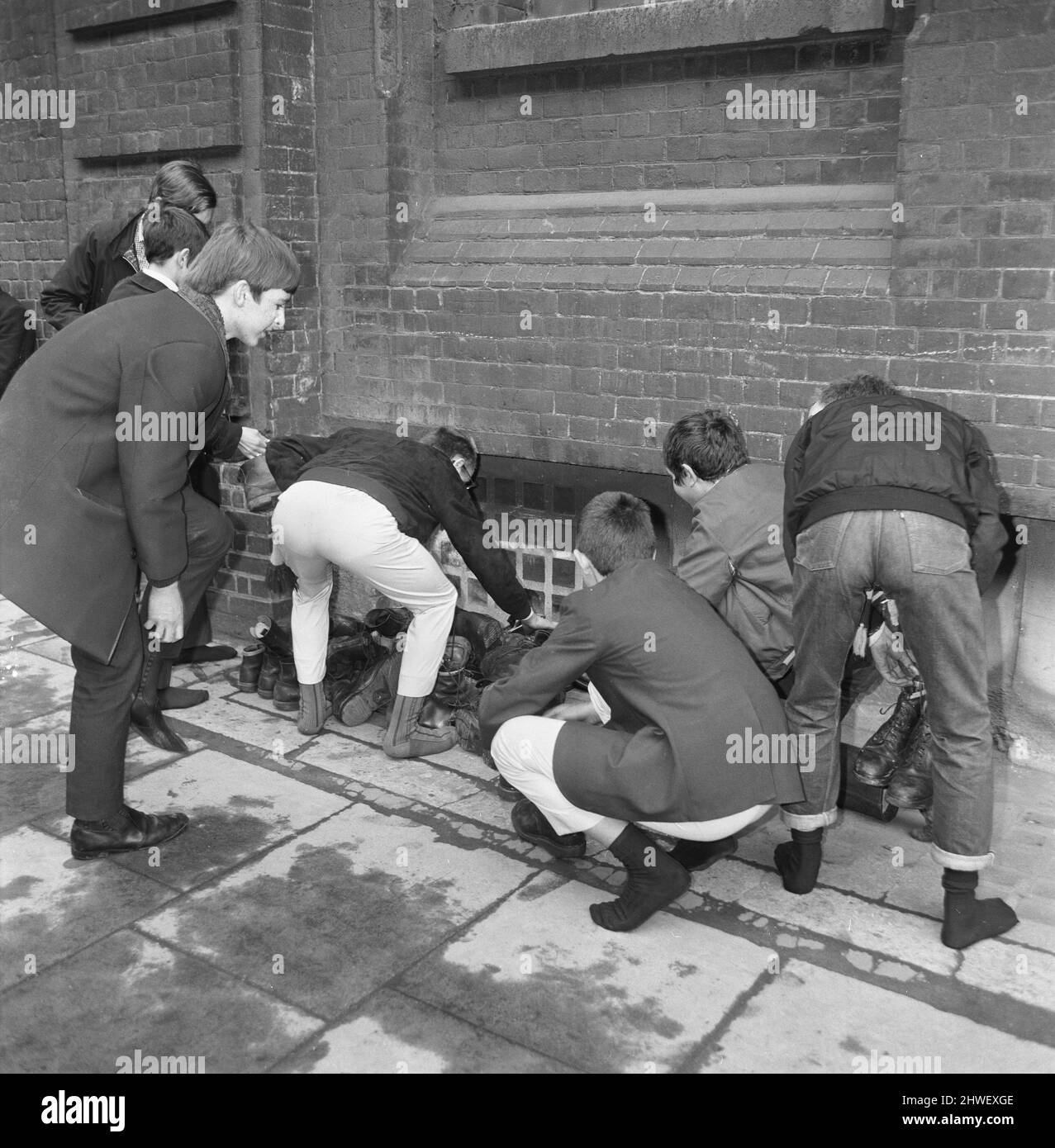Skinheads treffen sich in der Farringdon Road, London. Zwanzig bis dreißig Jugendliche wurden entlang der Farringdon Road verfolgt, nachdem sie einen verbebten Zug und einen angeblichen Angriff auf einen Mann verübt hatten. Die Häupter wurden angehalten und mussten ihre Stiefel ausziehen, während die Polizei sie an einer Wand anstellte und sie durchsuchte. Bild zeigt: Jugendliche sammeln ihre Stiefel nach polizeilichen Ermittlungen. 4.. April 1970. Stockfoto