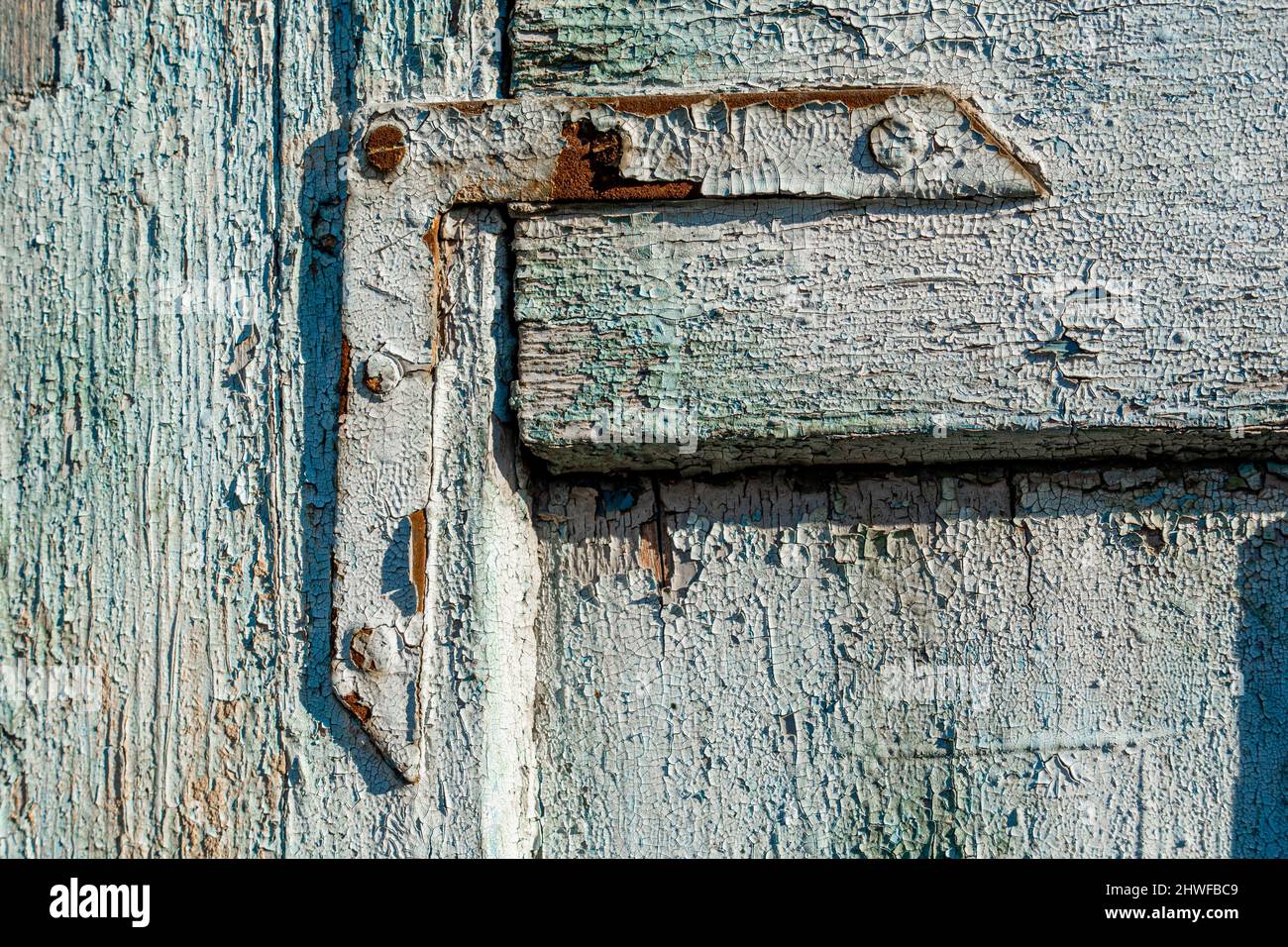 Blaue Farbe auf einem alten Eckhalter aus Metall an der Holztür mit verwitterter Farbe Stockfoto