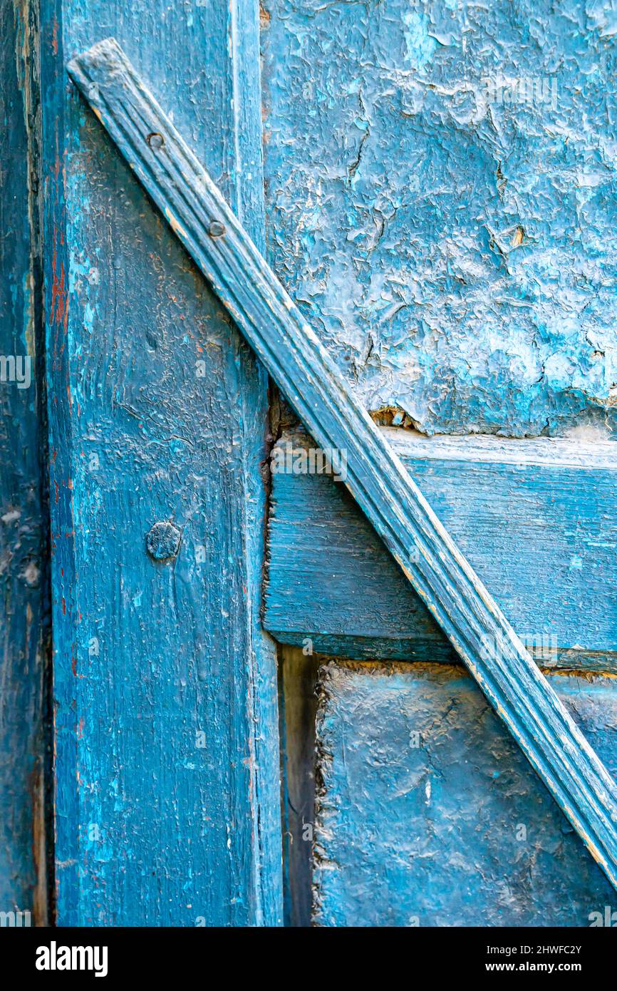 Blaue Farbe schälte sich an einer alten Holztür mit verwitterter Farbe Stockfoto