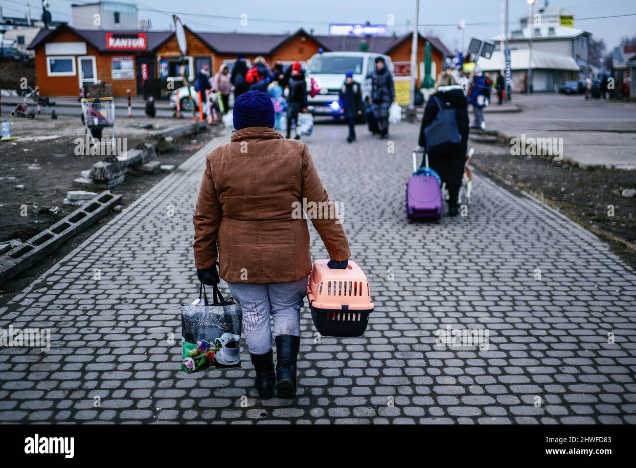 Die ukrainische Frau, die vor dem Krieg flüchtet, trägt eine Schachtel mit einem Haustier am ...