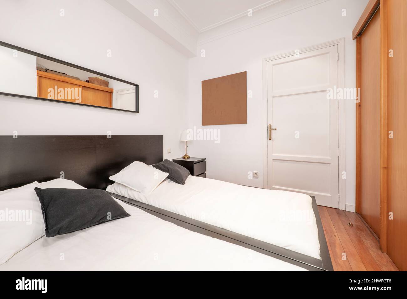 Schlafzimmer mit Doppelbetten, Kopfteil aus dunklem Holz und Einbauschrank mit Schiebetüren aus Kirschholz Stockfoto