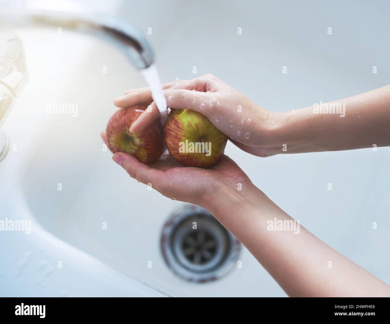 Im Begriff, einige saftige Äpfel zu genießen. Schuss einer Person, die Äpfel unter fließendem Wasser wäscht. Stockfoto