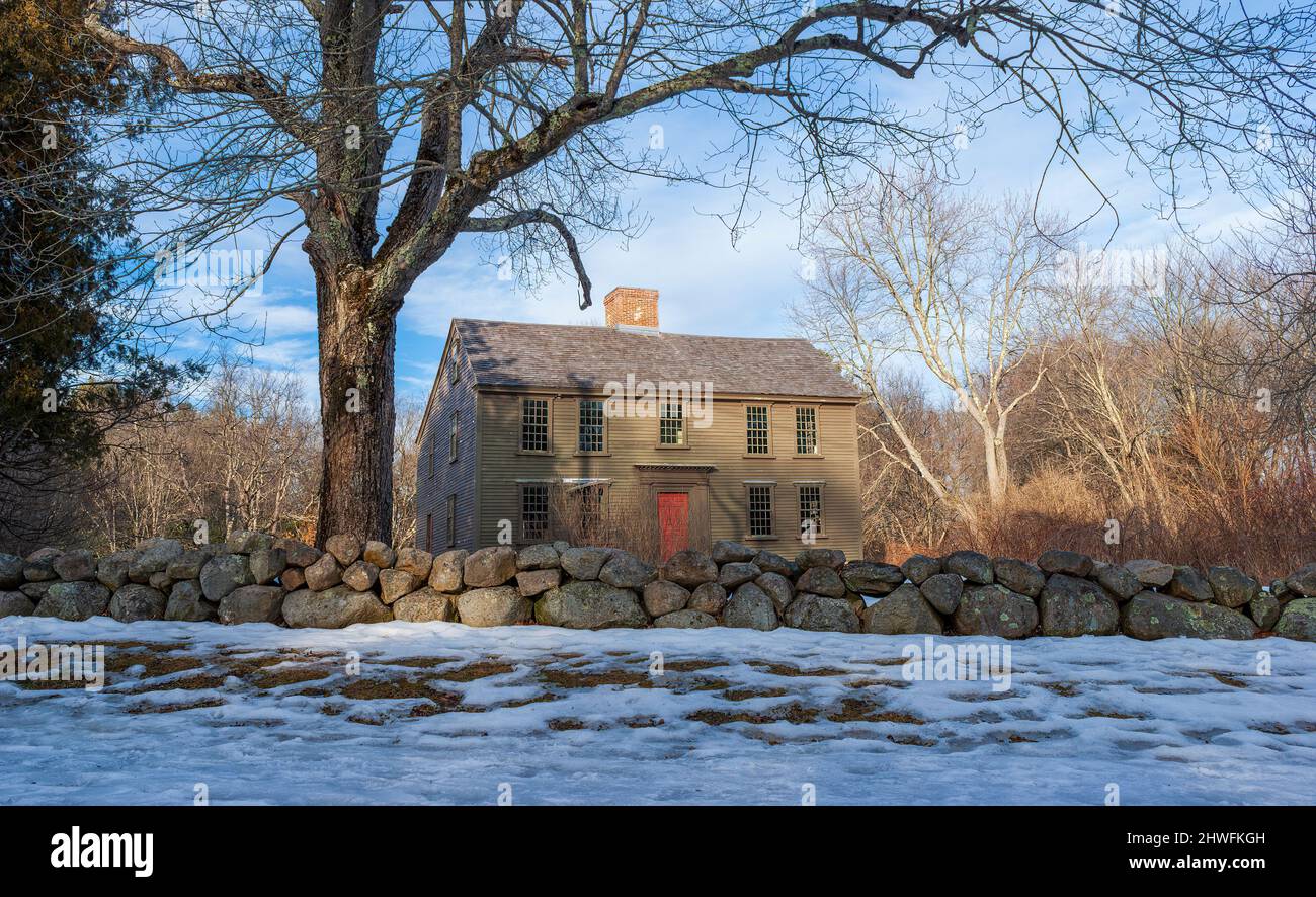 Das Jacob Whittemore House im Winter, hinter einer Steinmauer, umgeben von blattlosen Bäumen. Minute man National Historical Park, Lexington, MA. Stockfoto