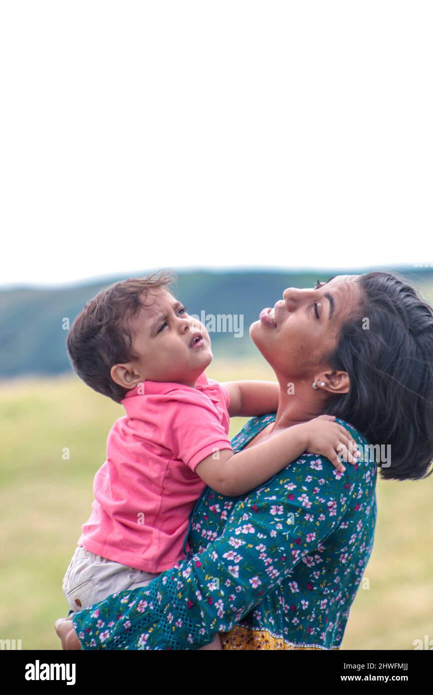 Die alleinerziehende lateinische Mutter und ihr Sohn blicken in einem grünen Feld in den Himmel Stockfoto