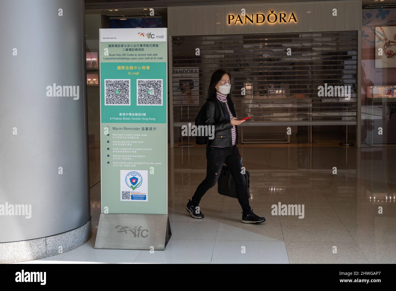 Zero Covid Hongkong. Omicron. 2022. Eine Frau geht durch die obligatorische Leave Home Safe App zur Kontaktverfolgung in einem Einkaufszentrum. Stockfoto