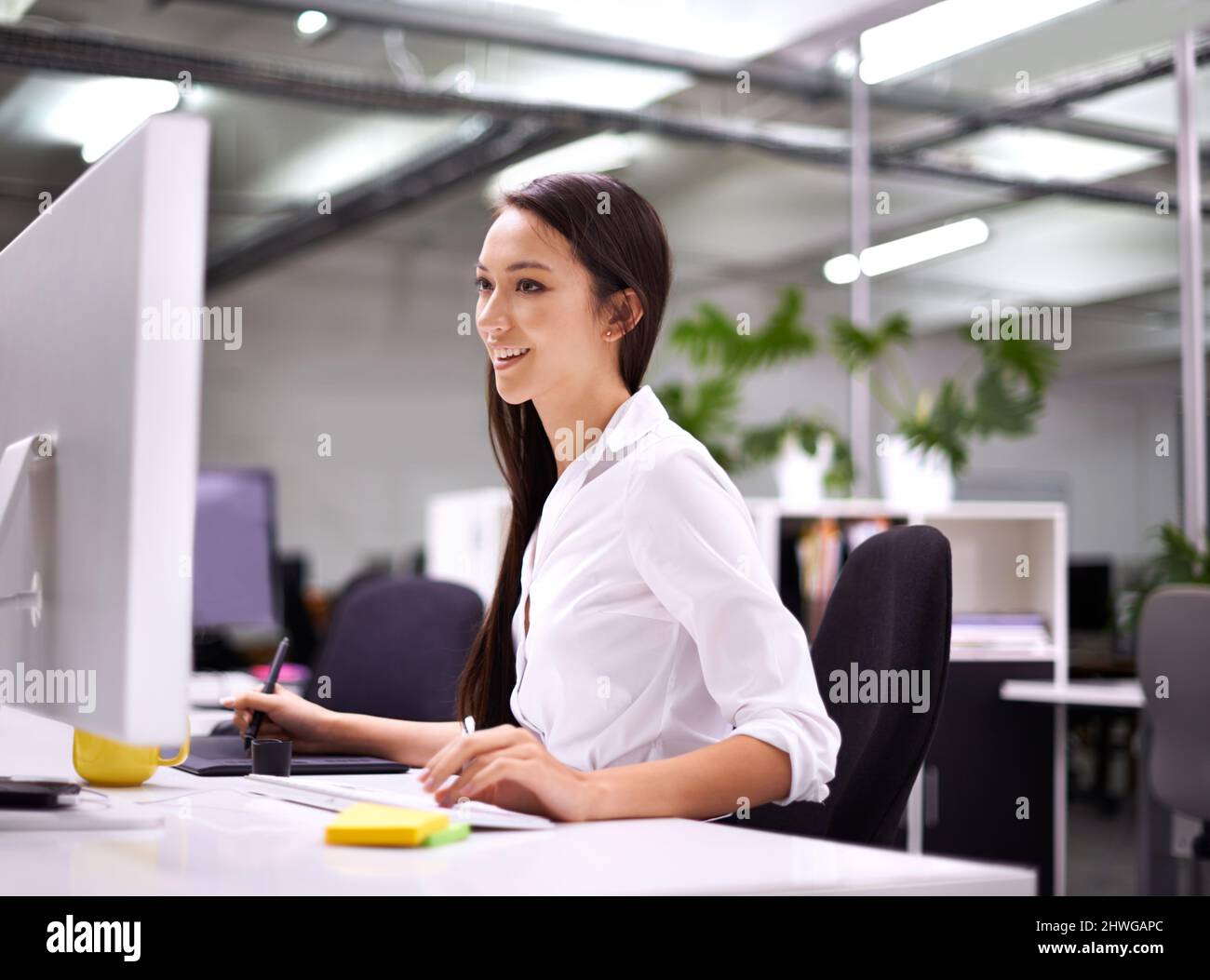 Genießen Sie jede Minute Arbeit. Eine kurze Aufnahme einer attraktiven jungen Frau, die an ihrem Schreibtisch arbeitet. Stockfoto