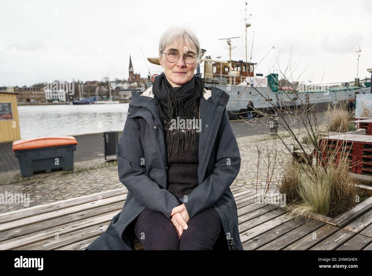 Flensburg, Deutschland. 22.. Februar 2022. Andrea Paluch, Schriftstellerin, Literaturwissenschaftlerin und Übersetzerin und Ehefrau des Politikers Robert Habeck, sitzt am Museumshafen der Flensburger Förde. (To dpa: 'Weltende und Sinnsuche - die Schriftstellerin Andrea Paluch') Quelle: Axel Heimken/dpa/Alamy Live News Stockfoto