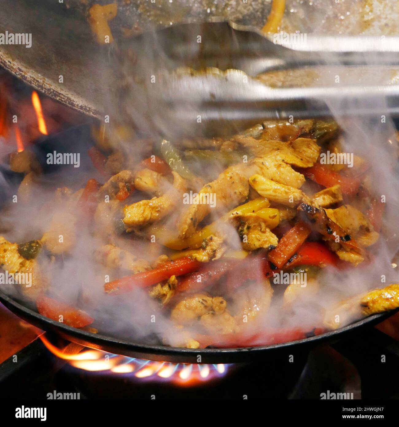 mexikanische Gerichte, Hühnerfajitas auf einem heißen, rauchenden, brutzelnden Teller Stockfoto