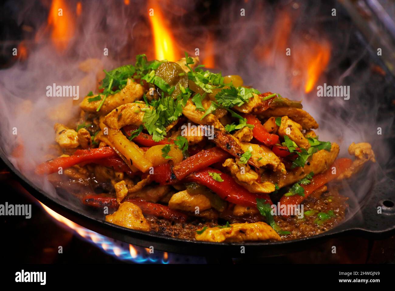 mexikanische traditionelle Speisen, Hühnchen Fajitas auf einem heißen, rauchenden, brutzelnden Teller serviert Stockfoto