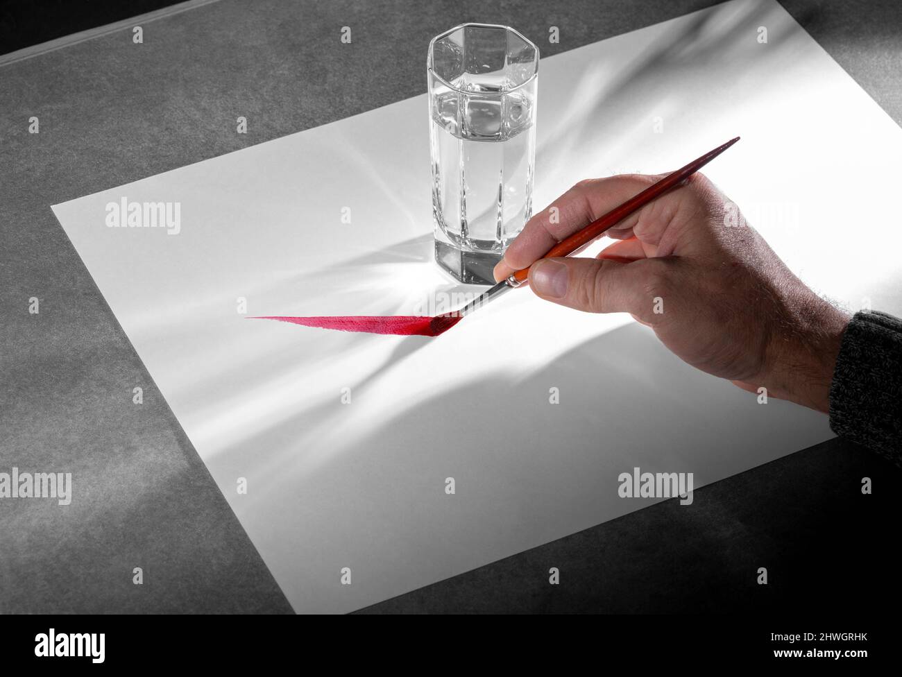 Kunst und Handwerk Thema zeigt ein Gemälde Hand mit Pinsel und eine Reihe von Farbe auf weißem Papier Blatt einschließlich einem Glas Wasser Stockfoto