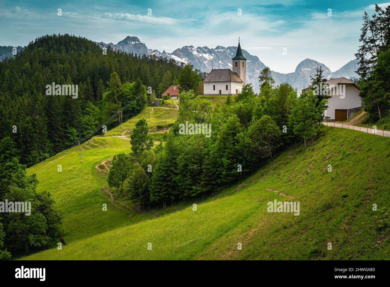 Slowenische Berglandschaft und kleine Kirche auf dem Hügel. St. Spirit ( Sveti Duh) Kirche und Kamnik-Savinja Alpen im Hintergrund, Slowenien, Europa Stockfoto