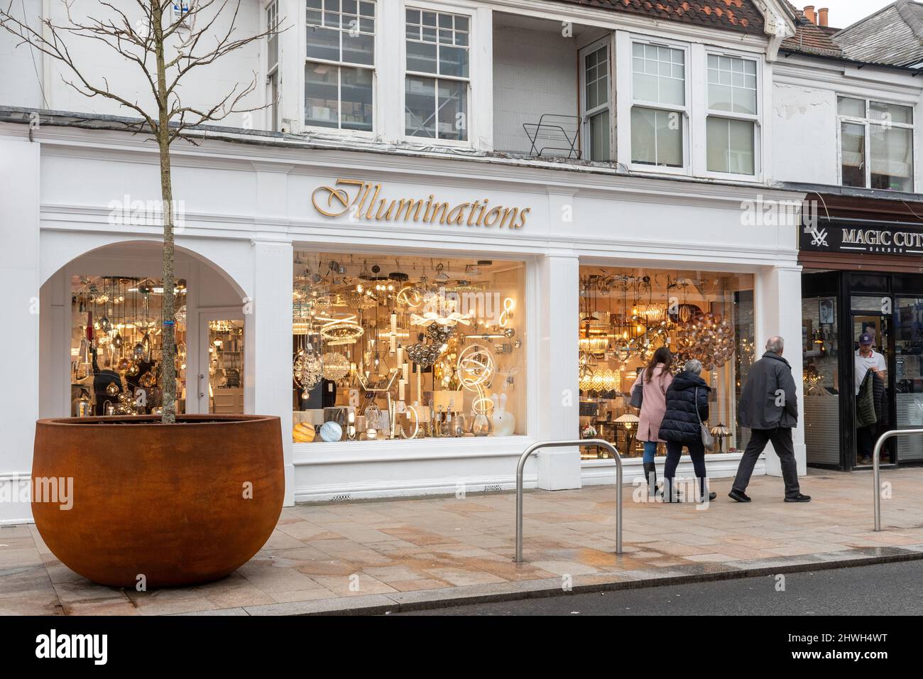 Menschen, die an Illuminations vorbeilaufen, einem Laden, der Lichter und Beleuchtung verkauft, im Stadtzentrum von Camberley, Surrey, England, Großbritannien Stockfoto