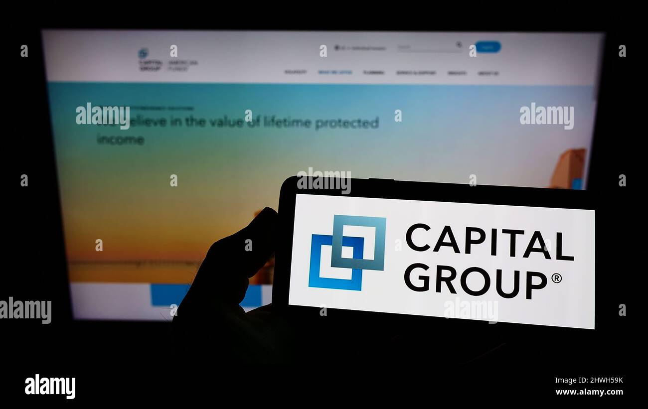 Person, die Mobiltelefon mit dem Logo der US-Finanzgesellschaft Capital Group Companies Inc. Auf dem Bildschirm vor der Webseite hält. Konzentrieren Sie sich auf die Telefonanzeige. Stockfoto