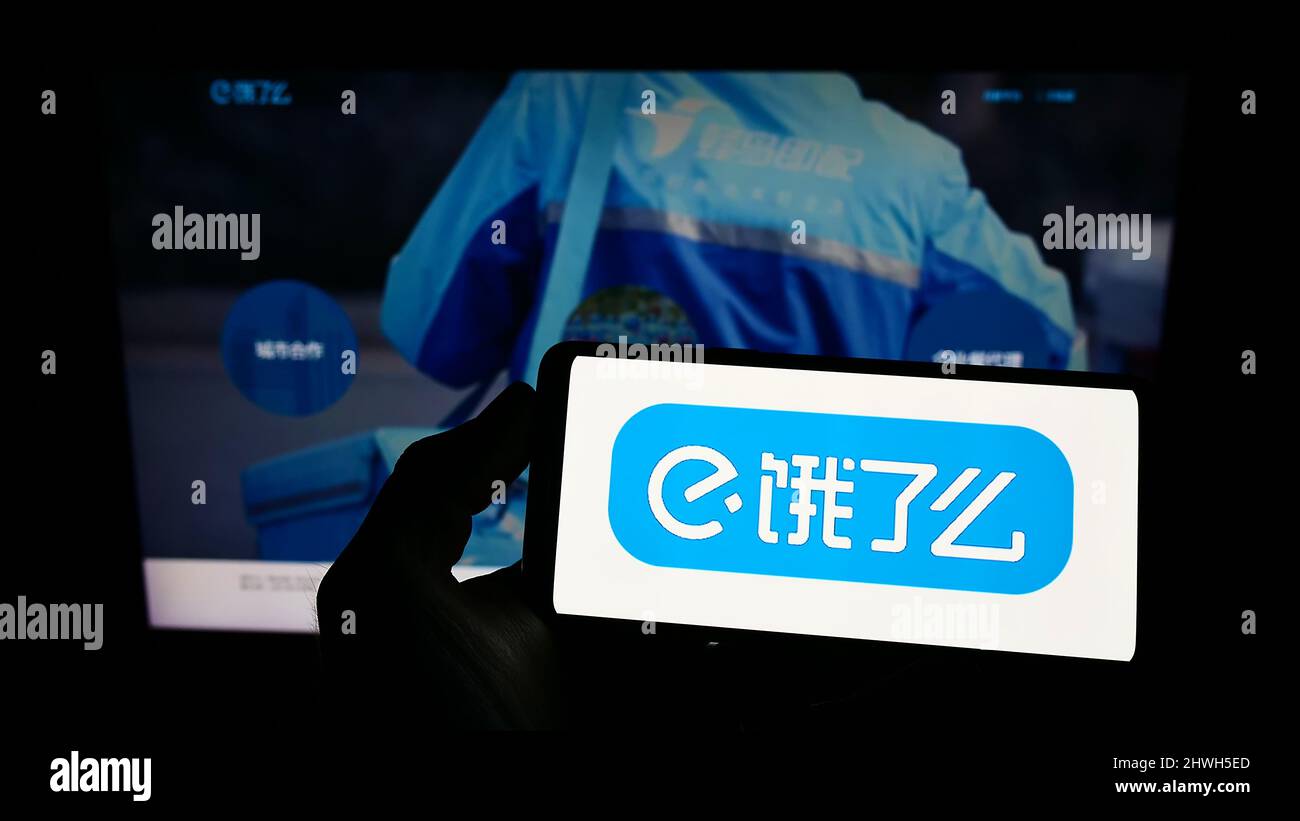 Person, die ein Mobiltelefon mit dem Logo des chinesischen Lebensmittellieferungsunternehmens ELEME Inc. (Ele.me) auf dem Bildschirm vor der Webseite hält. Konzentrieren Sie sich auf die Telefonanzeige. Stockfoto