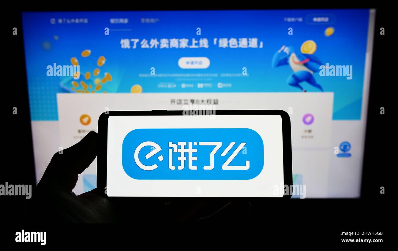 Person, die Mobiltelefon mit dem Logo des chinesischen Lebensmittellieferungsunternehmens ELEME Inc. (Ele.me) auf dem Bildschirm vor der Webseite hält. Konzentrieren Sie sich auf die Telefonanzeige. Stockfoto