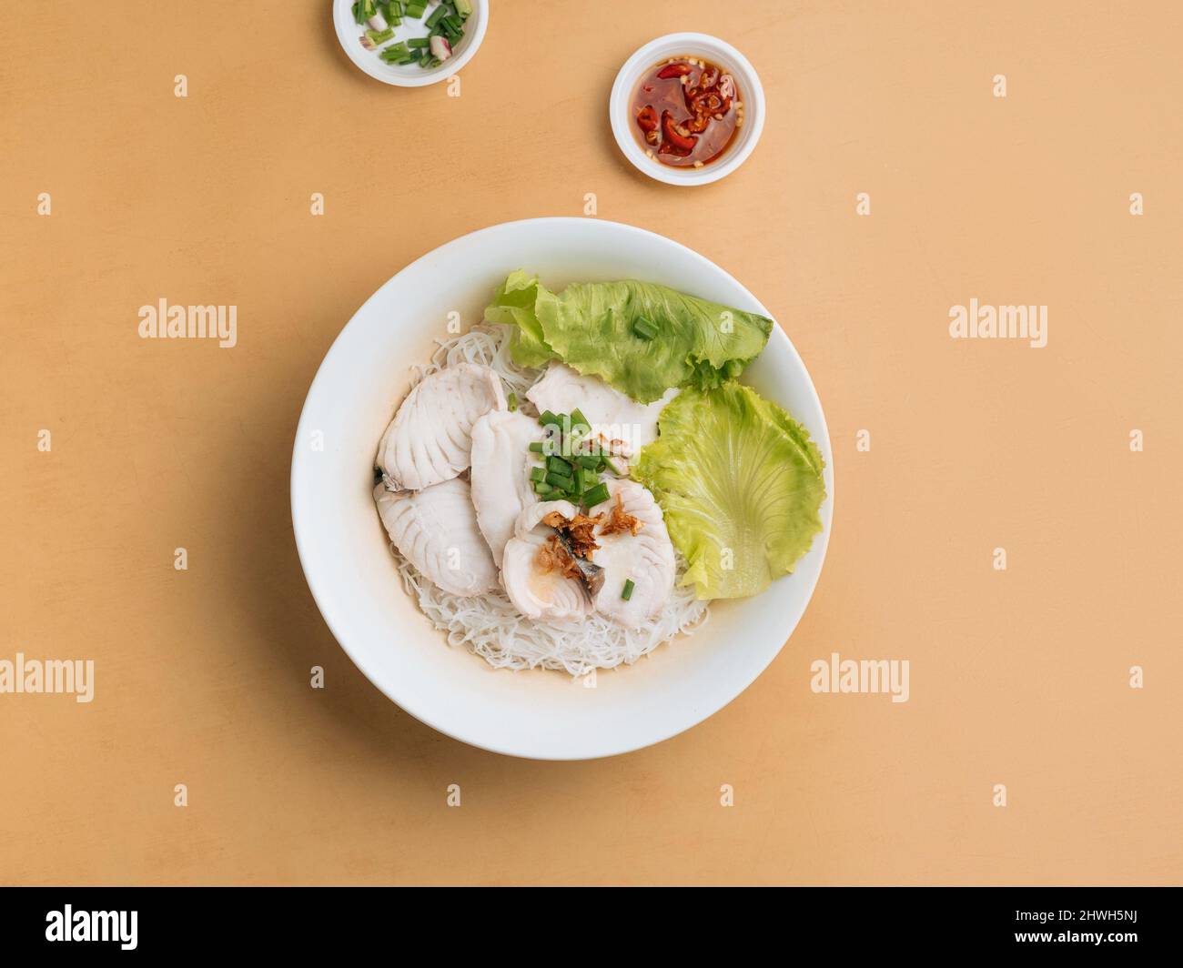 singapore Food Fish Bee Hoon in Scheiben geschnitten in einer Schüssel mit Suppe, Chilisauce und Frühlingszwiebeln Draufsicht auf Holztisch Stockfoto