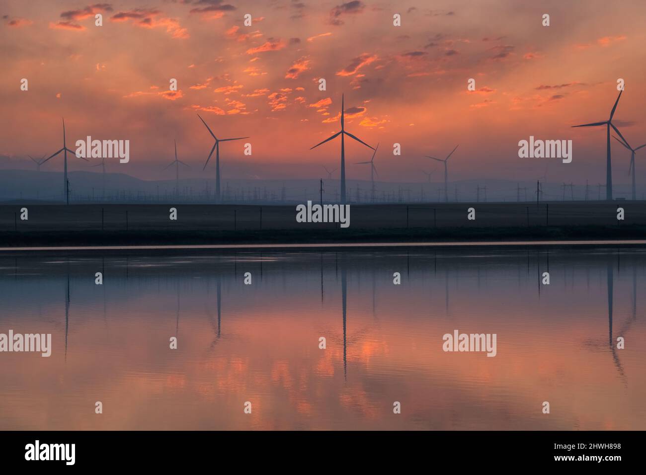 Windmühle Turbinen bei Sonnenaufgang mit Reflexion Stockfoto