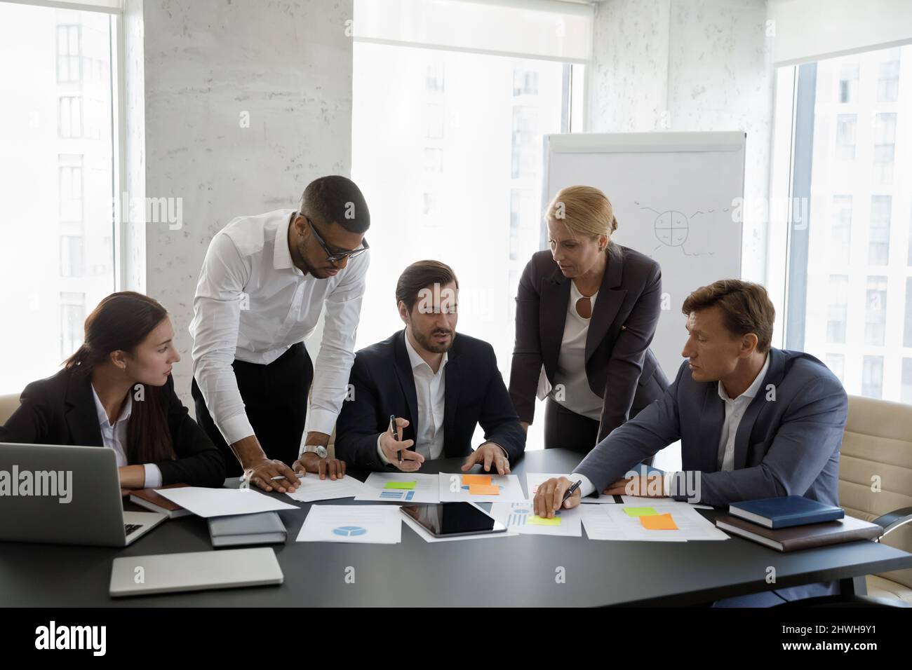 Gruppe fokussierter junger seriöser multirassischer Kollegen, die Papierkram machen. Stockfoto