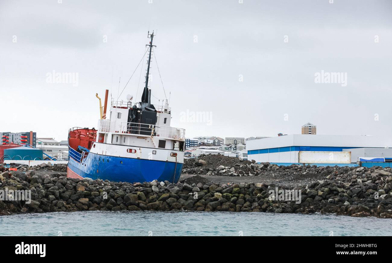 Das Trawler-Schiff liegt an einer felsigen Küste im Hafen von Reykjavik, Island Stockfoto