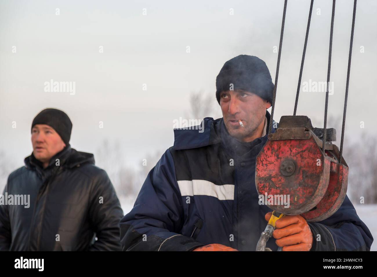 Der Schleuder zieht eine Bandschlinge am Haken eines LKW-Krans an Stockfoto