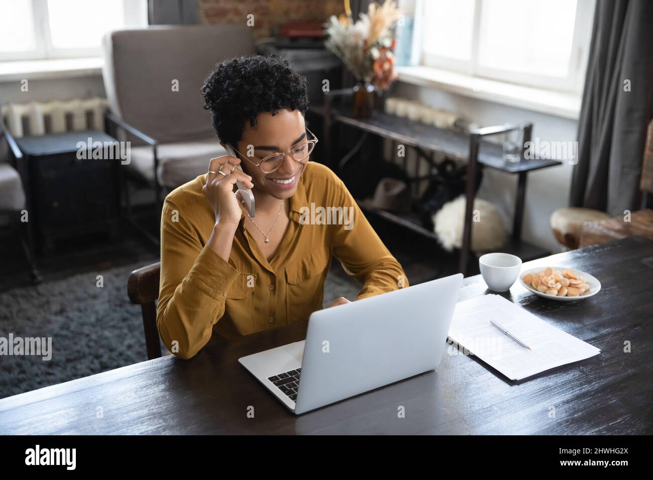 Happy Black freiberuflicher Mitarbeiter mit Brille und Fernbedienung nimmt Anruf an Stockfoto