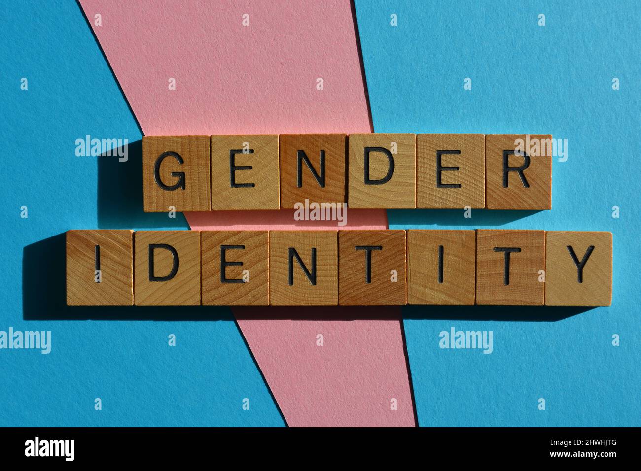 Geschlechtsidentität, Wörter in Holzbuchstaben isoliert auf rosa und blauem Hintergrund Stockfoto