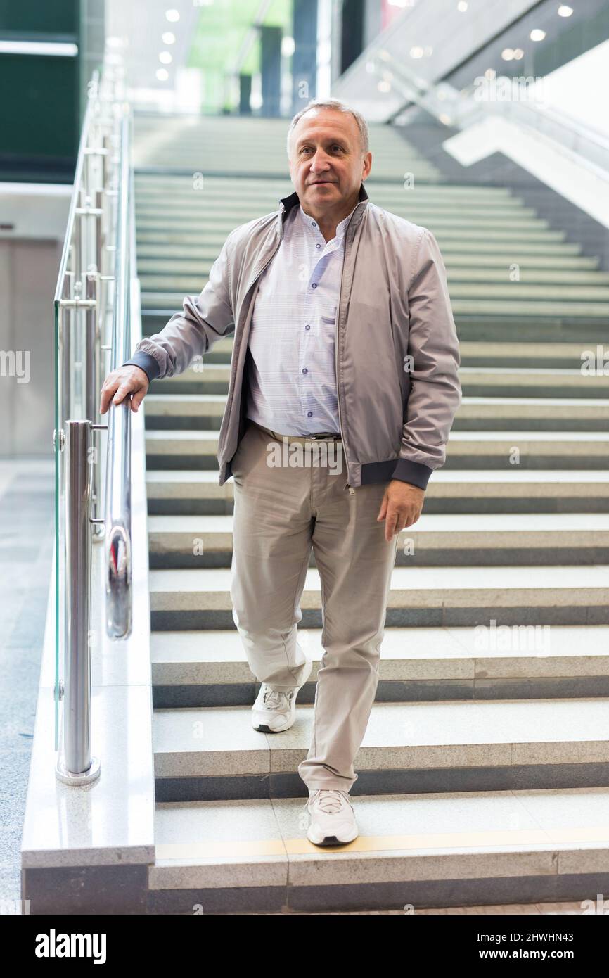 Mann mittleren Alters, der die Treppen in der Mall hinuntergeht Stockfoto