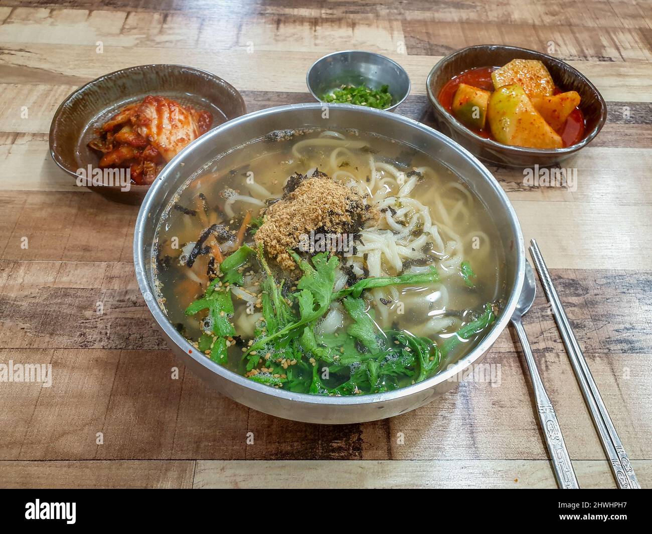 Kal-guksu, ein koreanisches Nudelgericht, das aus handgefertigten, messerschnitten Weizenmehl-Nudeln besteht und in einer großen Schüssel mit Brühe und anderen Zutaten serviert wird. Stockfoto