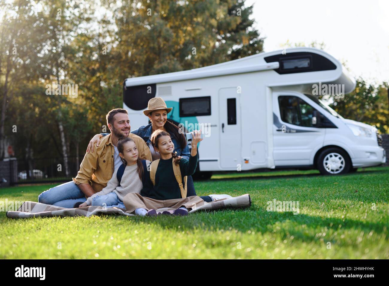 Glückliche junge Familie mit zwei Kindern, die im Freien Selfie mit Wohnwagen machen. Stockfoto