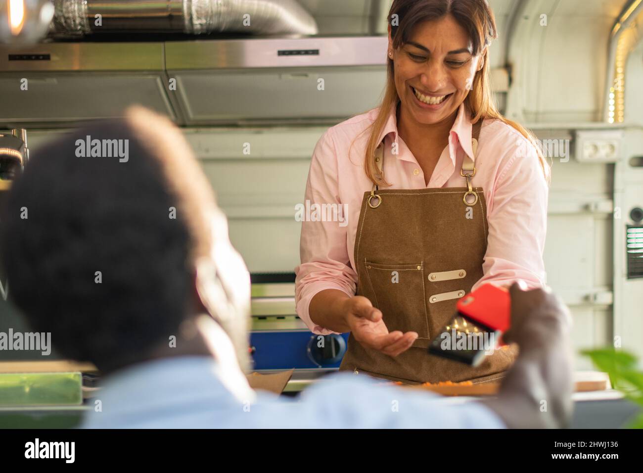Schwarzer Mann, der mit dem Smartphone in einem Food Truck bezahlt Stockfoto
