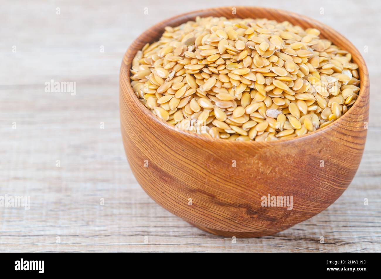 Die Goldflachskerne in einer Holzschale auf braunem Hintergrund. Stockfoto