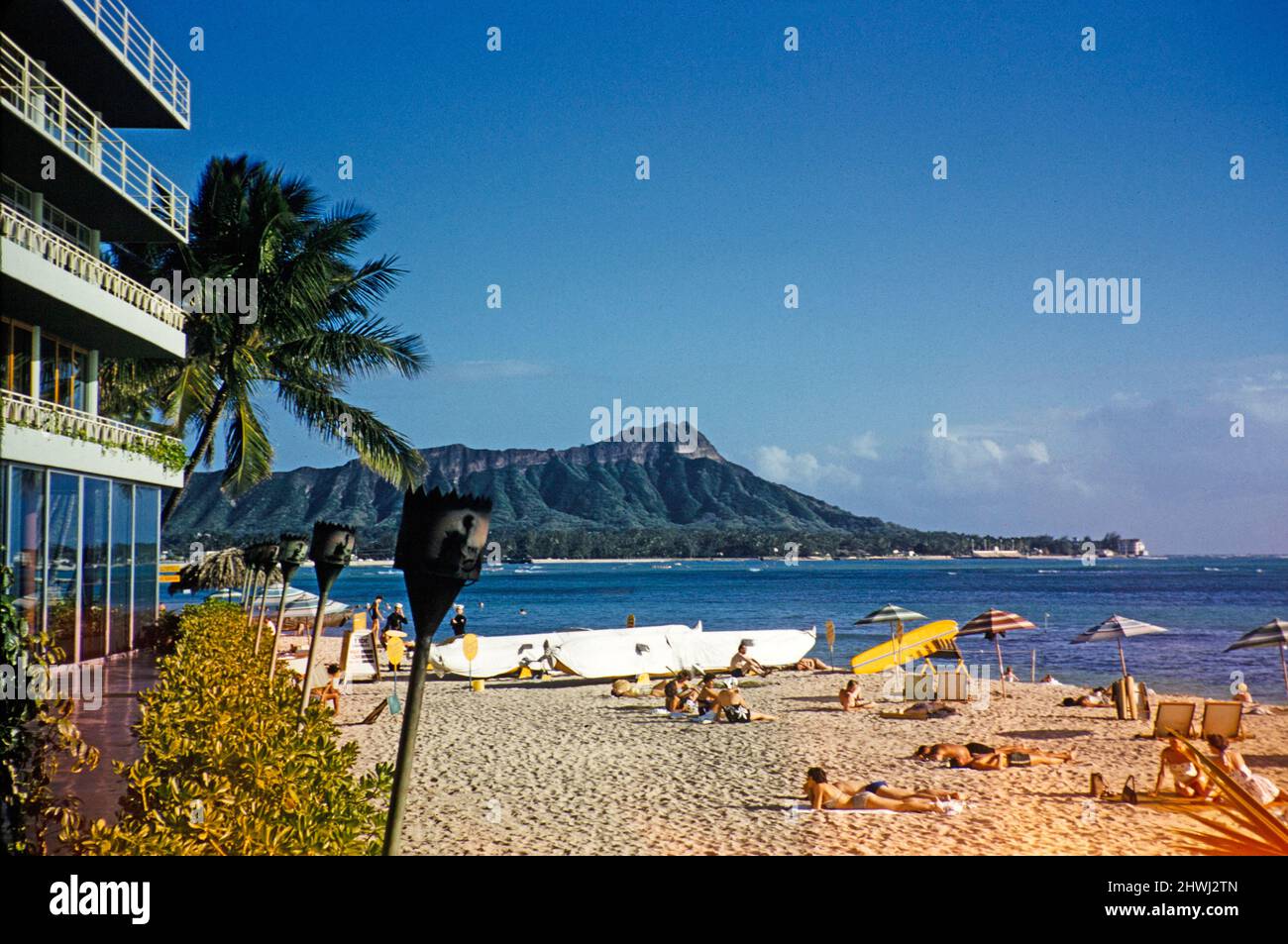 Sonnenbaden am Sandstrand des Reef Hotels, heute Outrigger Reef Hotel, Honolulu, Hawaii, USA im Jahr 1956 - das erste große Hotel, das am Strand von Waikiki gebaut wurde. Diamond Head im Hintergrund. Stockfoto
