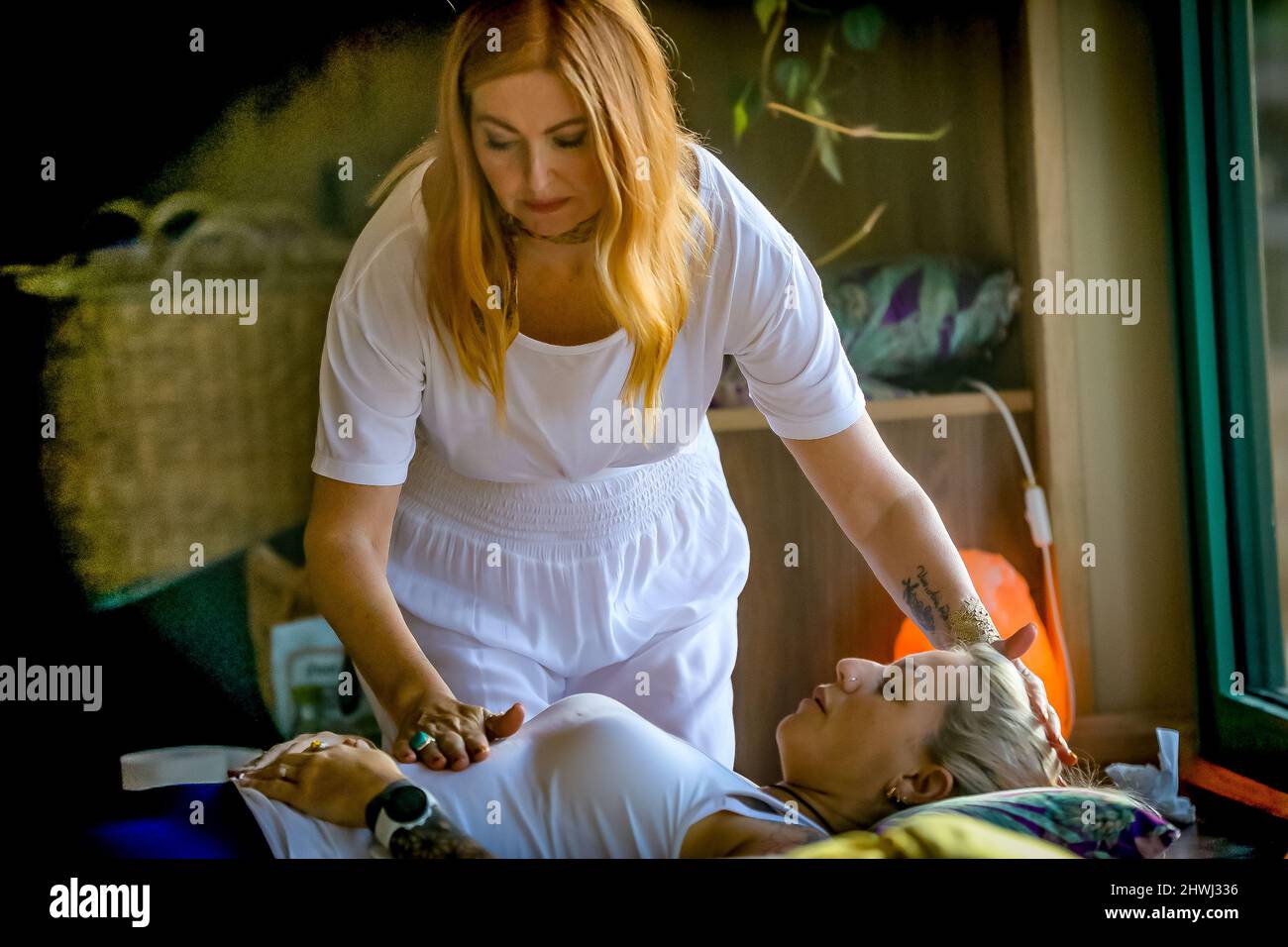 Jacqui Cooper entformte einem europäischen Weibchen der 30er Jahre ein Energieversiegelung, im Kreis bei einer Cacao-Zeremonie in ihrer Maloka. Stockfoto