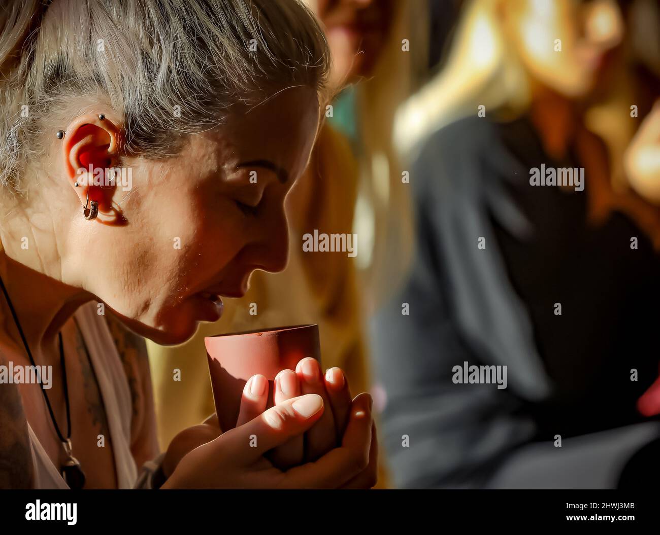 Eine europäische Hündin aus den 30er Jahren hält ihren Kakaokasse in Herz-Chakra bei einer Kakaozeremonie im Beachyjax-Heilzentrum Maloka, mit Sitz in Honley, West Yorkshire, Großbritannien. Stockfoto