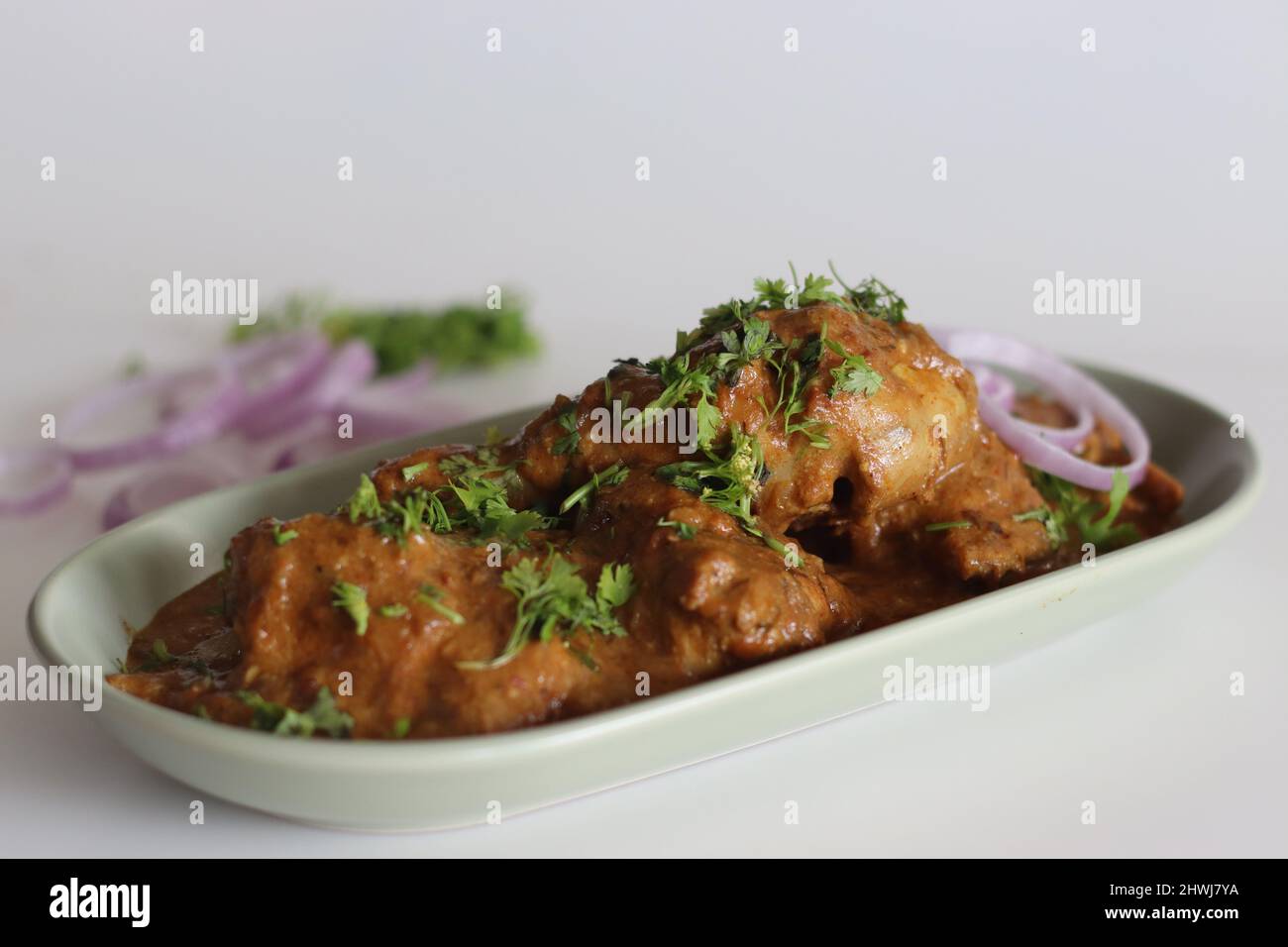 Hühnercry, zubereitet von Hühnchen in Cashew-Soße, garniert mit frischen Korianderblättern. Aufgenommen auf weißem Hintergrund Stockfoto