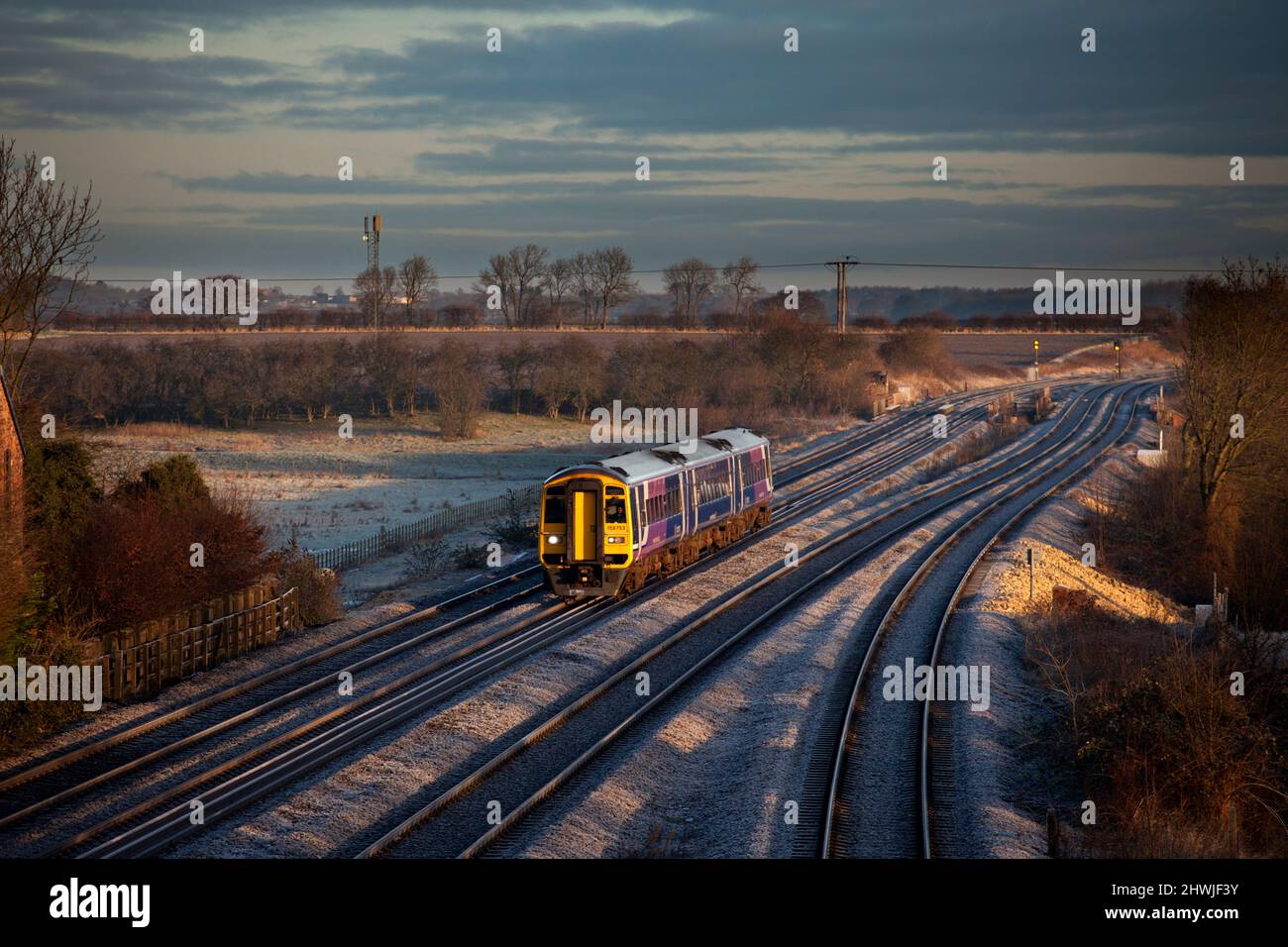 Nördlicher Schnellzug der Baureihe 158 158753 bei Sonnenaufgang im Winterlicht, der auf einer 4-spurigen Eisenbahn mit Frost am Boden verläuft Stockfoto