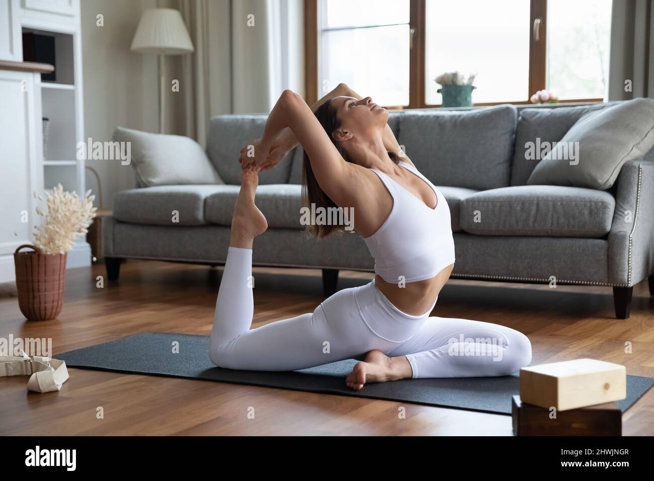 Frau übt Yoga Stretching in einer einbeinigen King Pigeon Asana Stockfoto