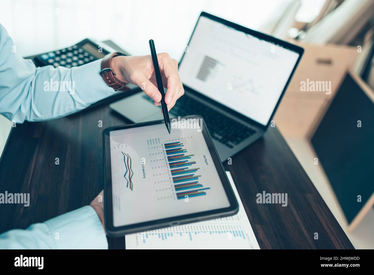 Business Hand Hold Stylus Pen Touchscreen digitales Tablet mit Business-Diagramm auf dem Tisch-Arbeitsplatz. Stockfoto