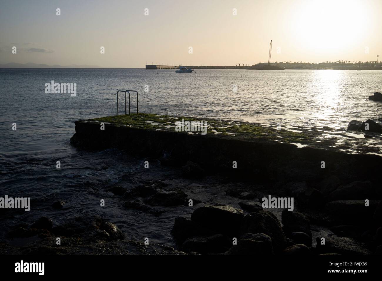 Sonnenuntergang über Badeplattform und felsiger vulkanischer Küste playa blanca lanzarote, kanarische Inseln, spanien Stockfoto