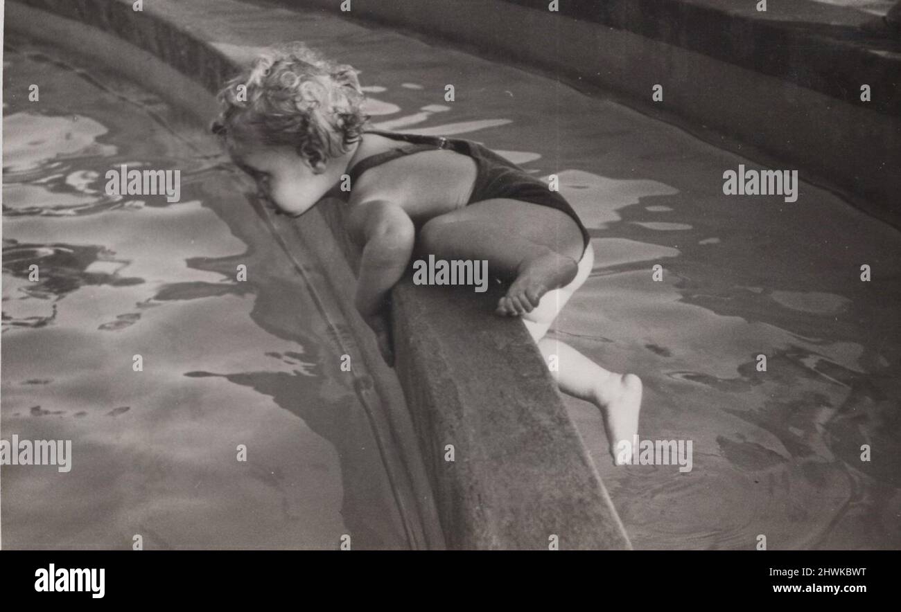 Vintage Schwarz-Weiß-Foto von einem kleinen Jungen klettert bis an den Rand eines Wasserbrunnens. Er springt fast ins Wasser. Gefährliche Manouver von ihm und Verantwortungslosigkeit von den Eltern. Zeitraum 1920s Quelle: Originalfoto. ADDITIONAL-RIGHTS-CLEARANCE-INFO-NOT-AVAILABLE Stockfoto