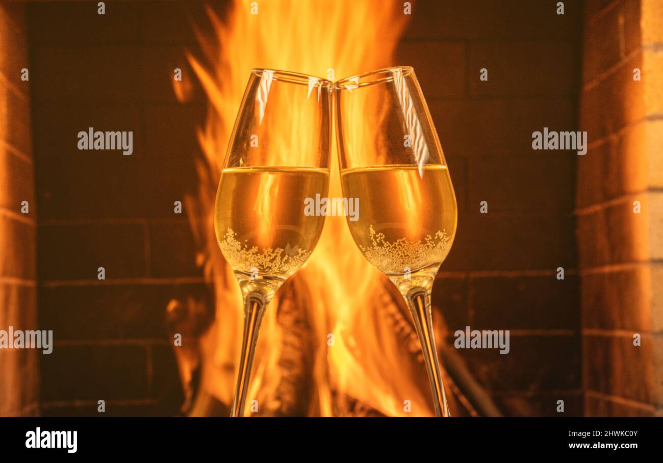Zwei Gläser Champagner vor einem gemütlichen Kamin in einem Landhaus. Stockfoto