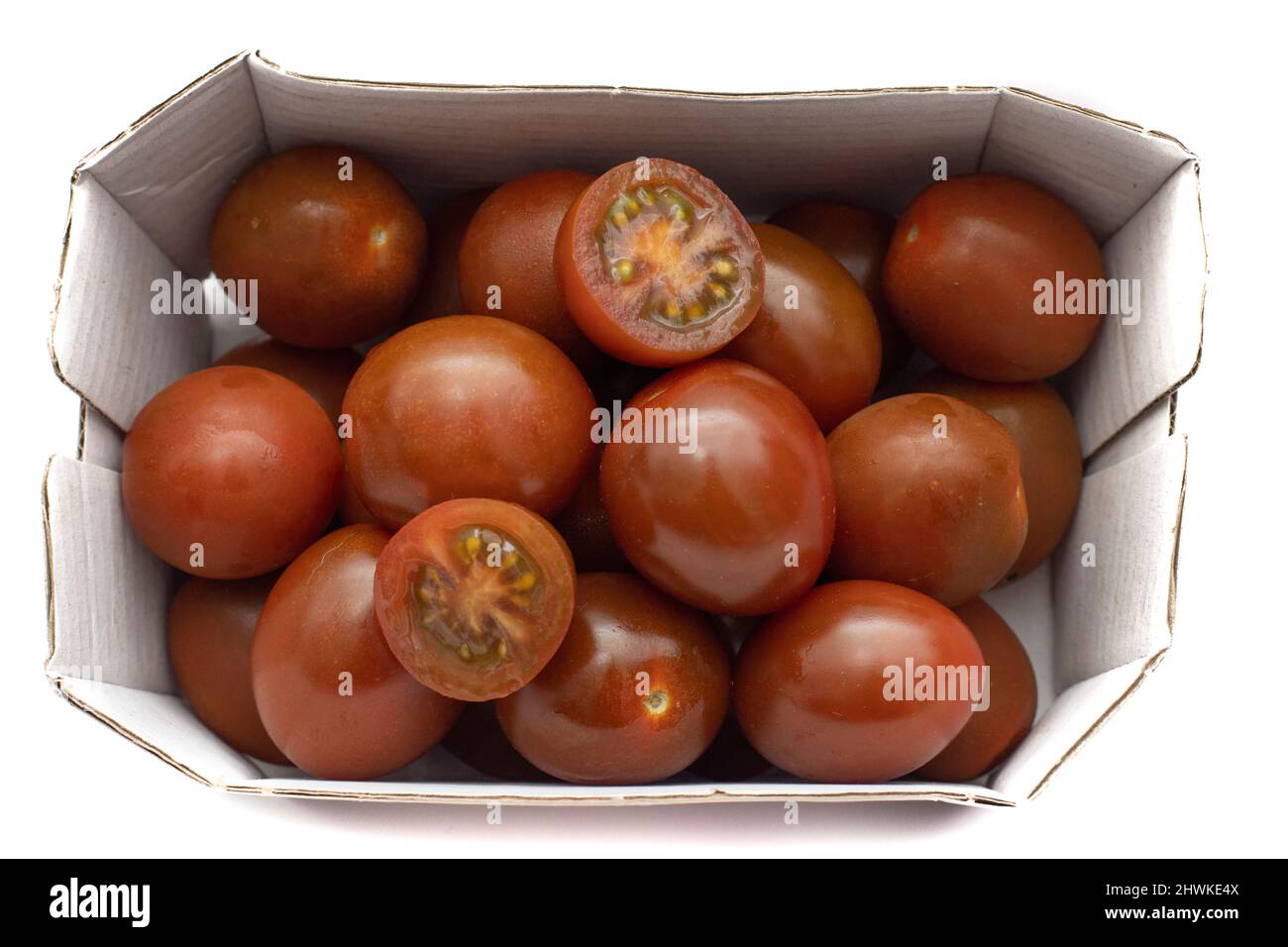 Ein Karton Kirschtomaten, die Mini-Kumato-Sorte. Isoliert auf weißem Hintergrund. Stockfoto